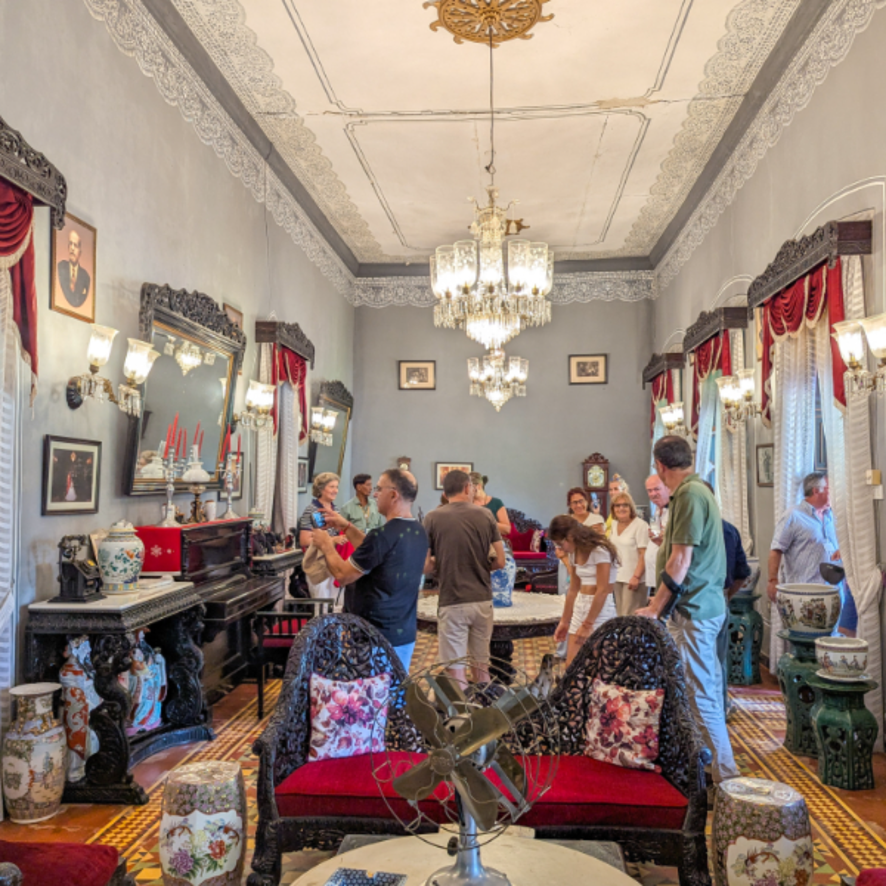 Bustling antique shop filled with ornate furniture, vases, mirrors, and chandeliers, with people browsing.